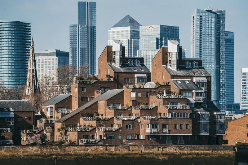 Red brick houses in front of the glass towers of the City of London
