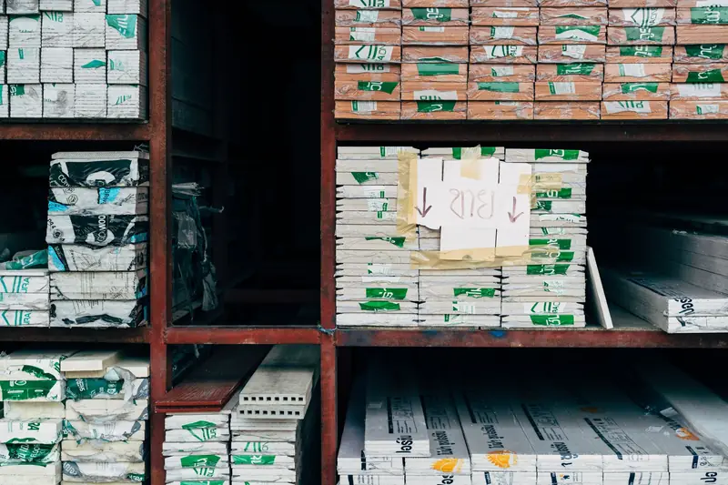 Racks in a building supplies warehouse stacked with wrapped bundles of building materials and boxed components