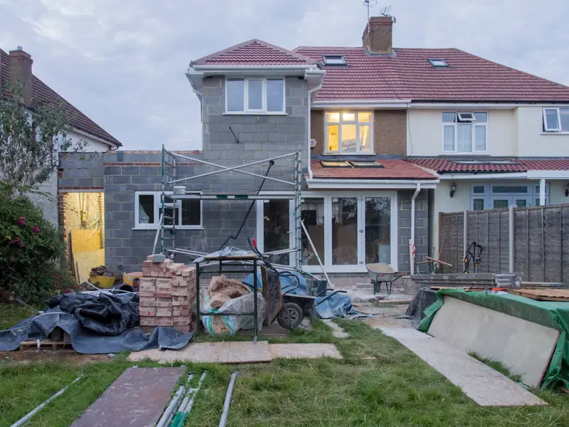 Suburban house under renovation with scaffolding and building materials